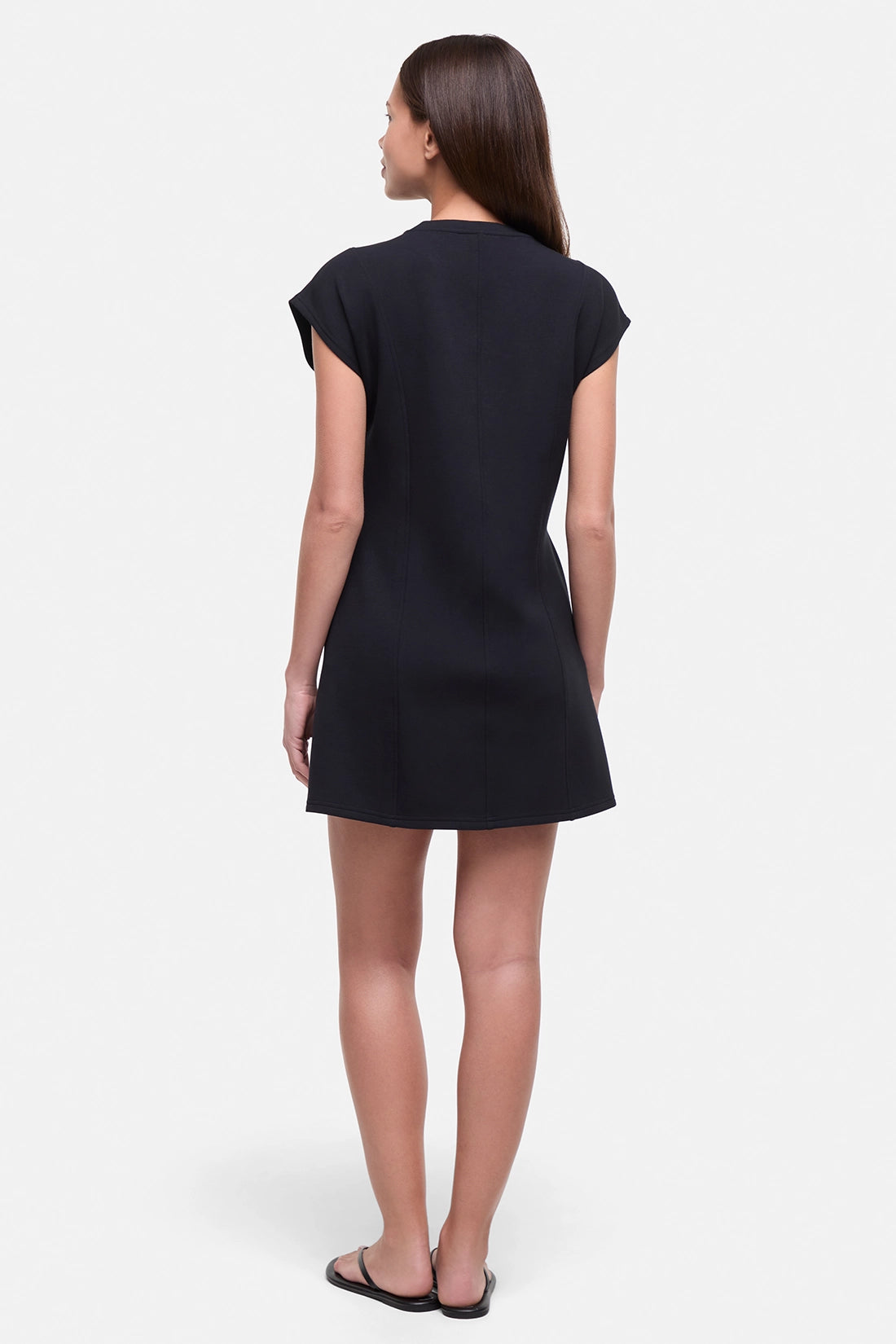 Back view of woman wearing a black mini dress on a white background.