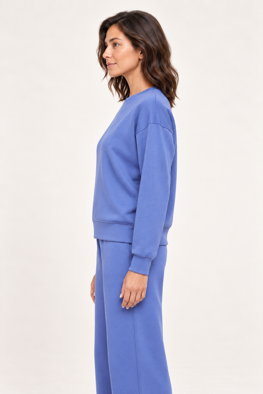 Woman wearing the blue Lana Pullover and matching pants, side studio view