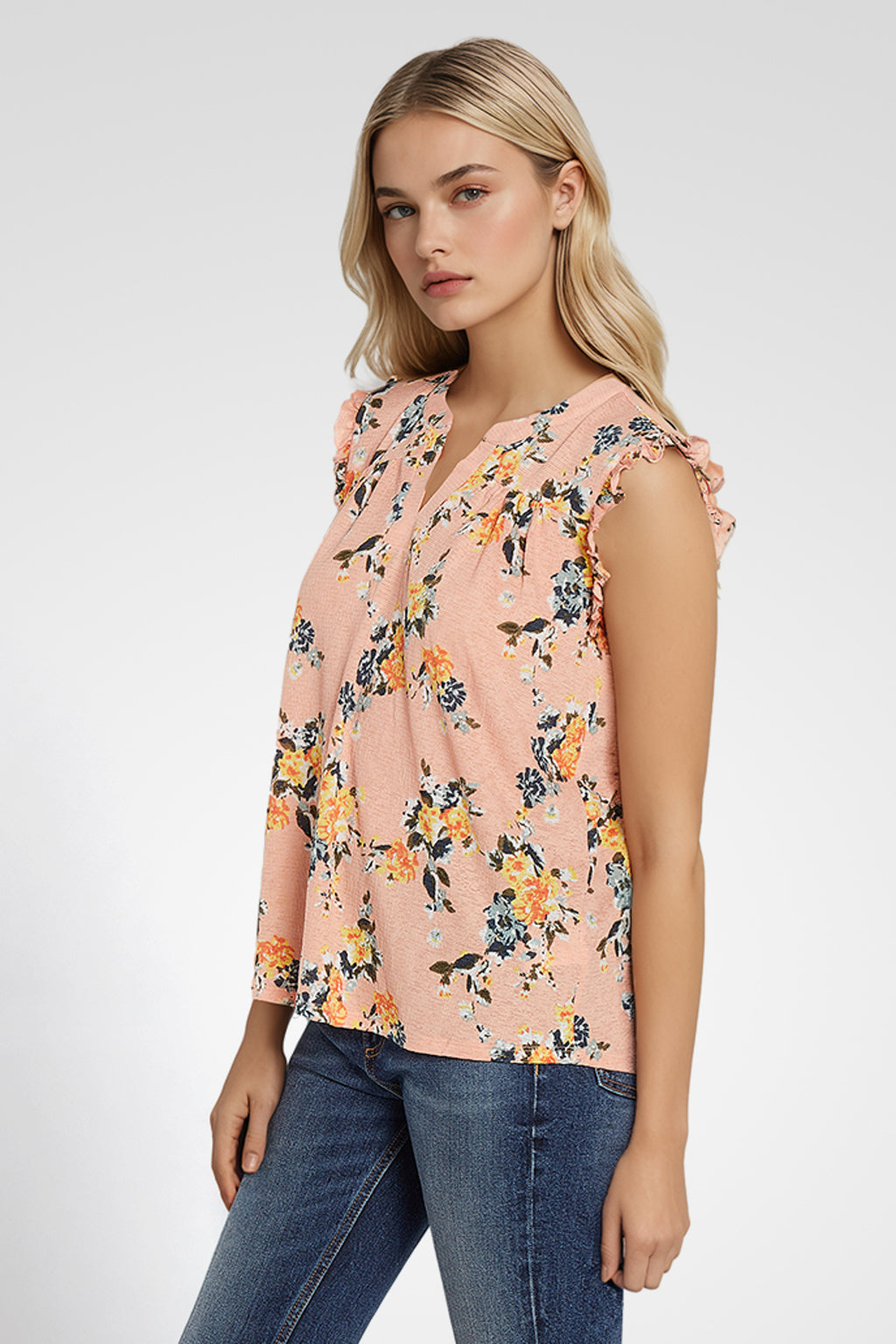 Woman wearing a sleeveless floral blouse with a plain background. coral-pink-yarrow