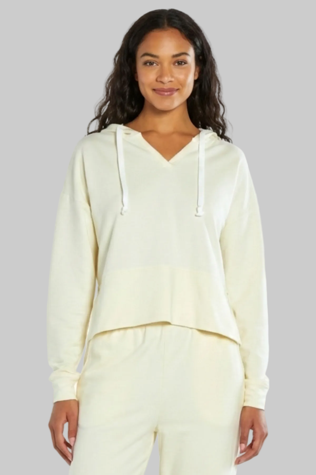 Woman wearing a cream-colored hoodie and pants on a white background