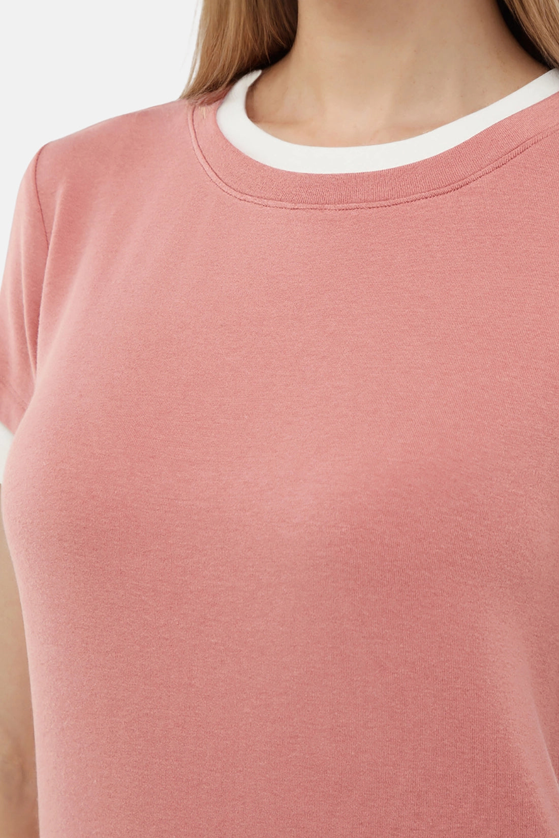 Close-up of a woman wearing a pink t-shirt with a white layered neckline.