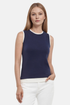 Front of woman wearing a navy tank with white layered hem and white pants on a light gray background. 