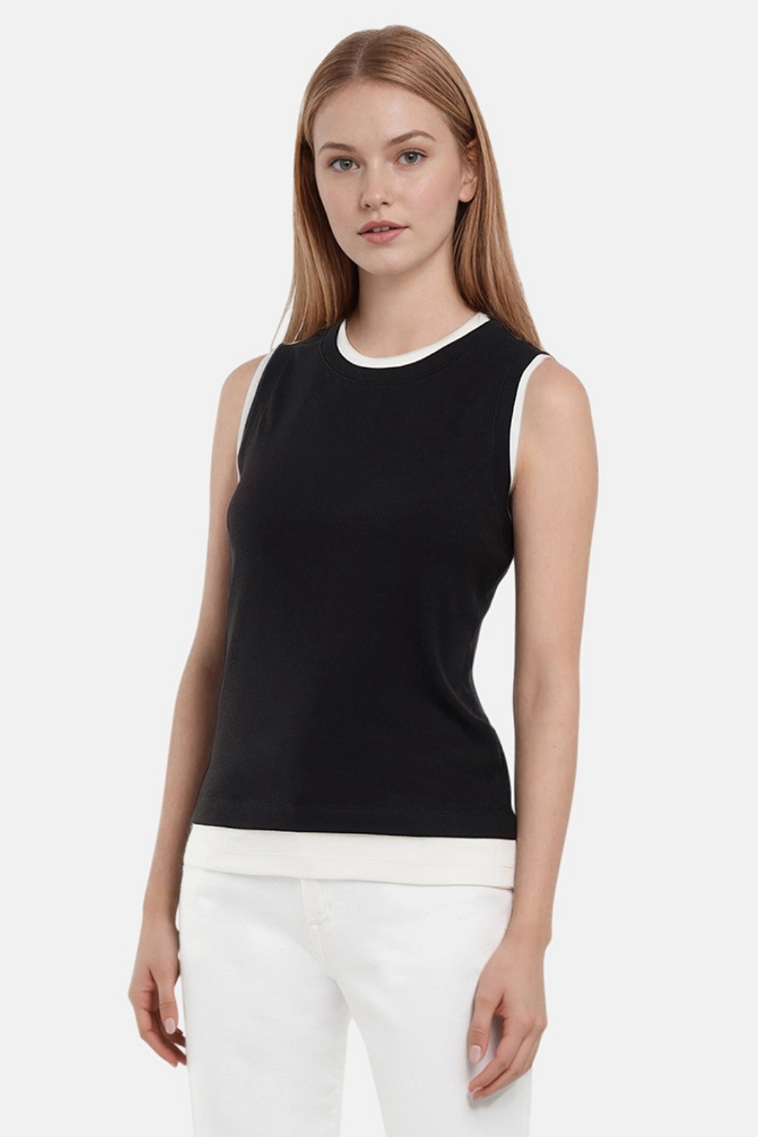 Front of woman wearing a navy black with white layered hem and white pants on a light gray background.