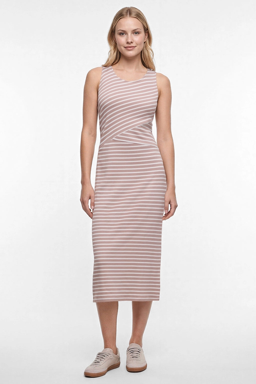 A woman modeling a sleeveless midi dress with horizontal light brown and white stripes, paired with beige sneakers, against a plain white studio background. #color_stucco-amy-stripe