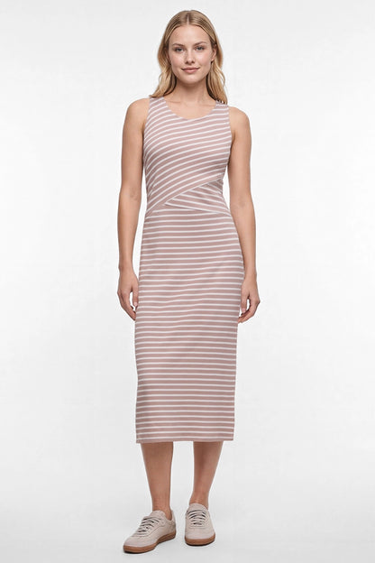 A woman modeling a sleeveless midi dress with horizontal light brown and white stripes, paired with beige sneakers, against a plain white studio background. 
