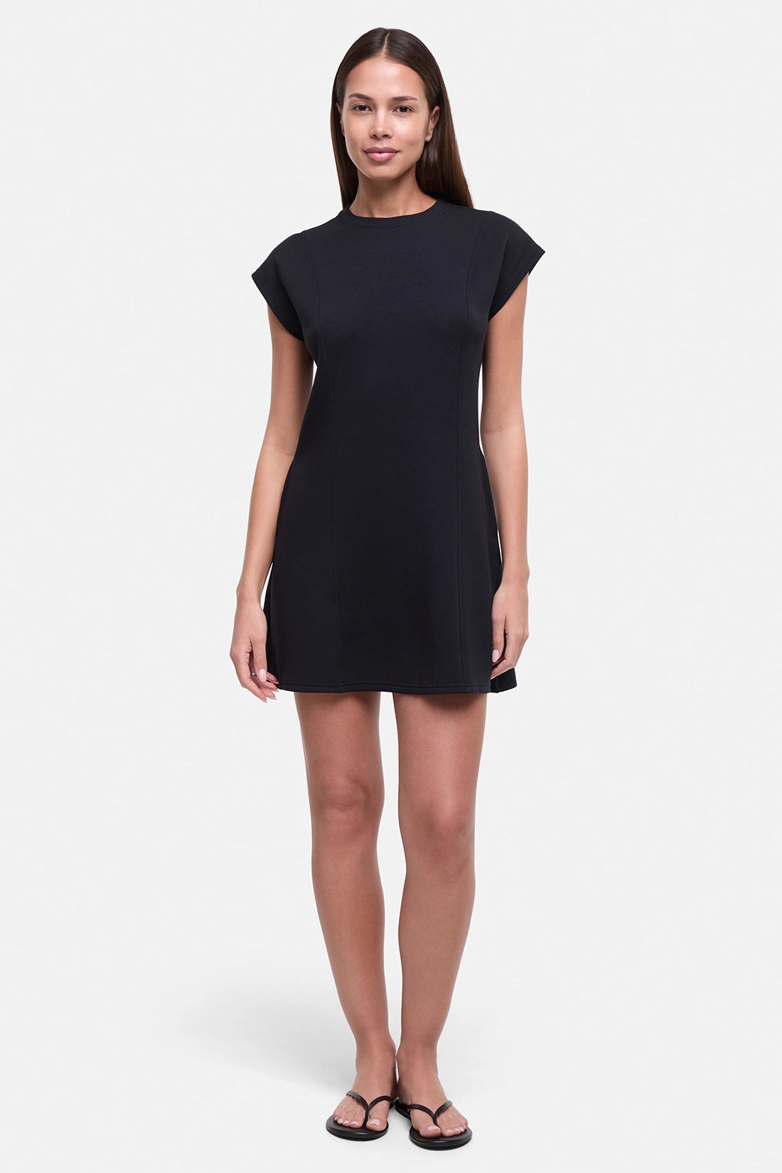 Front view of woman wearing a black mini dress on a white background.