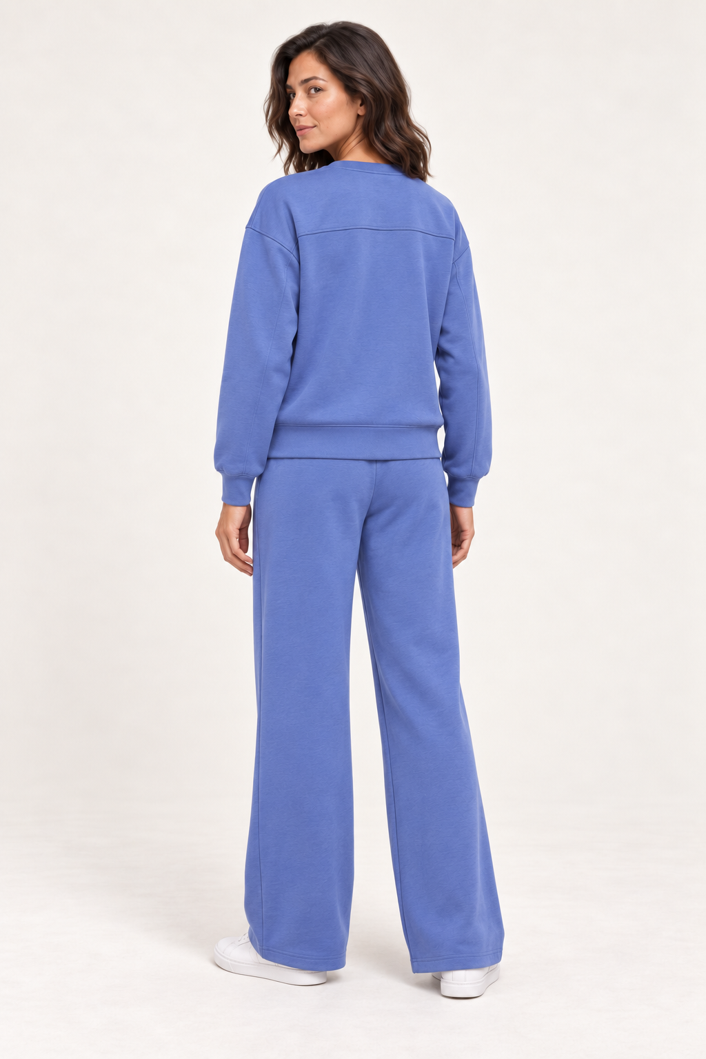 Woman wearing the blue Lana Pullover and matching pants, back studio view