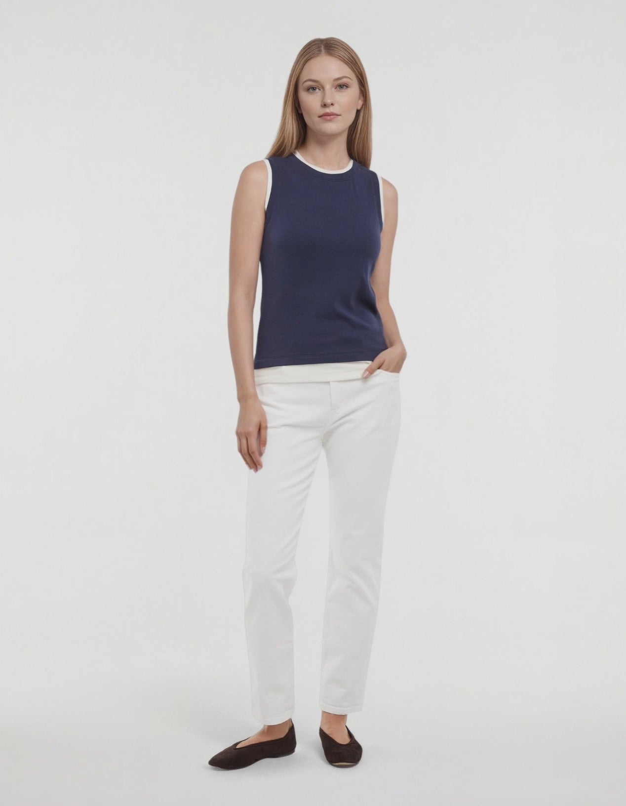 Video of woman wearing a navy tank with white layered hem and white pants on a light gray background. #color_naval-academy