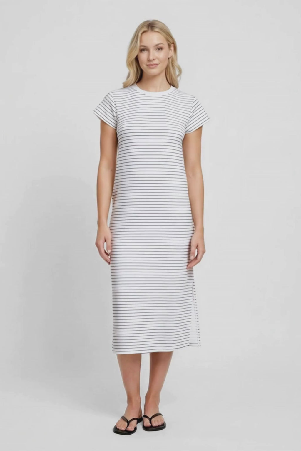 Video view of woman wearing a white and black striped midi dress with hand in pocket on a white background. #color_black-mini-stripe