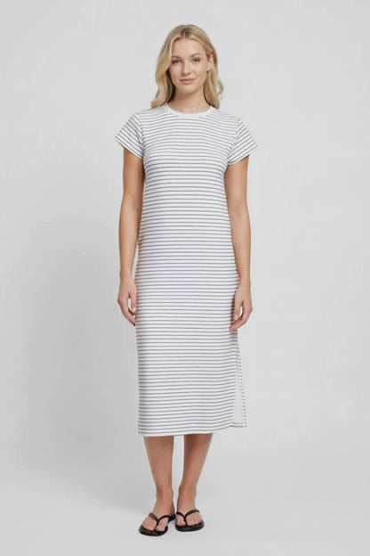 Video view of woman wearing a white and black striped midi dress with hand in pocket on a white background. 