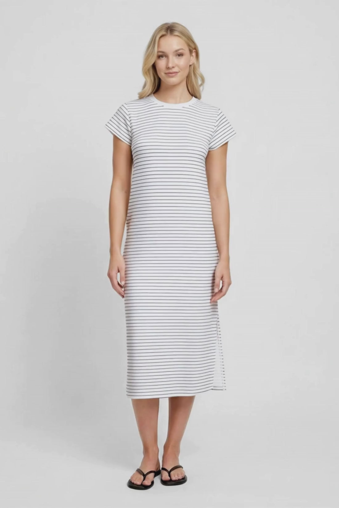 Video view of woman wearing a white and black striped midi dress with hand in pocket on a white background. #color_black-mini-stripe