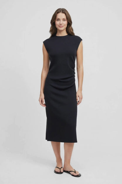 Video view of woman wearing a black sleeveless dress on a white background. 