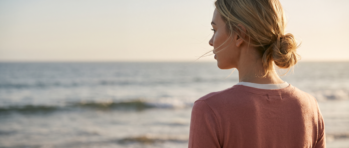 Woman by the ocean at golden hour in a dusty rose long sleeve tee